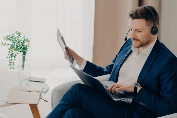 Busy young businessman working with documents at home remotely