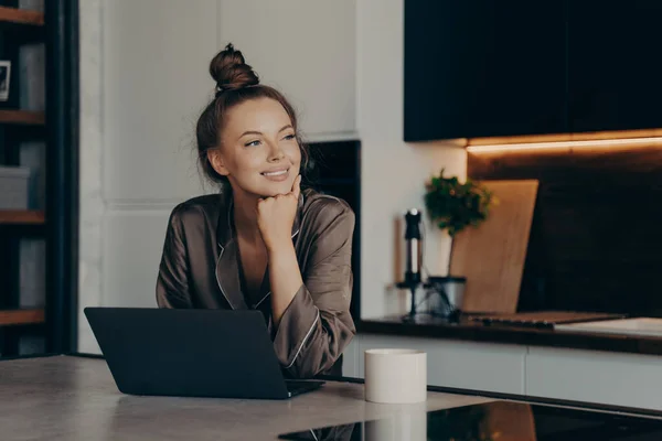 Jovem senhora freelancer feliz em pijama aconchegante trabalhando de casa no laptop — Fotografia de Stock