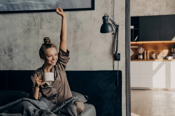 Atractiva joven feliz hembra tomando café de la mañana en la cama — Foto de Stock