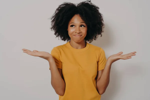 Jeune femme africaine debout avec une expression confuse sans idée et drôle avec les bras et les mains levées — Photo