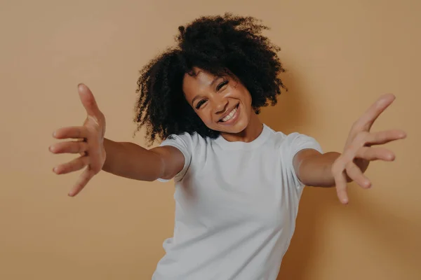 Beyaz gömlekli mutlu Afro-Amerikan kadın sarılıyor, müşteriyi karşılıyor.