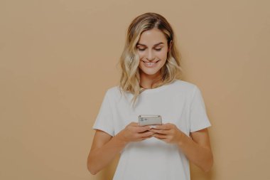 Genç mutlu kız akıllı telefon kullanıyor, erkek arkadaşıyla sosyal medyada sohbet ediyor ve gülümsüyor.