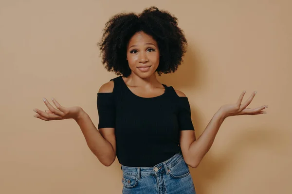 Femme afro inconsciente confus avec les cheveux bouclés ondulés, lève les mains dans la confusion — Photo