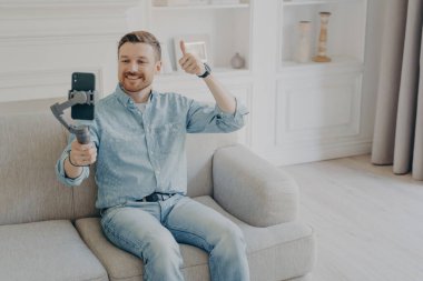Genç adam cep telefonunda kameraya baş parmak işareti yapıyor.