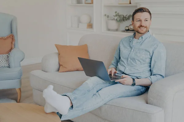 Relaxé jeune homme surf web tout en étant assis sur le canapé — Photo