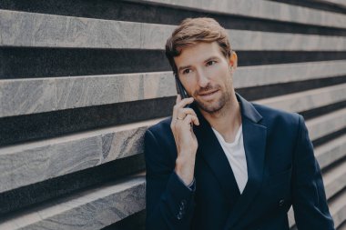 Mesafeli profesyonel girişimci resmi kıyafetler giyer, telefonda konuşur.