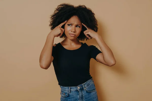 Young thoughtful mixed race woman holds fingers on temples and trying to concentrate — Stock Photo, Image