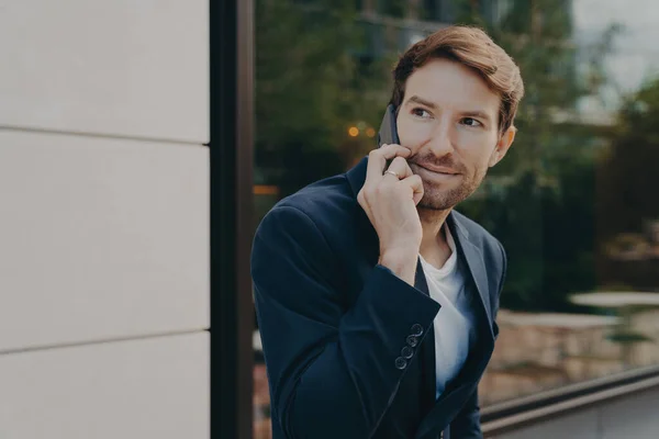 Bonito homem de negócios urbano profissional ouvindo o cliente no telefone celular enquanto estava fora — Fotografia de Stock