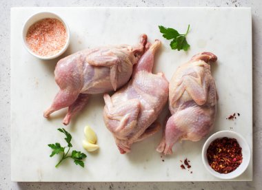 Beyaz taş levhada çiğ bıldırcın, tuz ve biber yakın plan. Düz yatıyordu