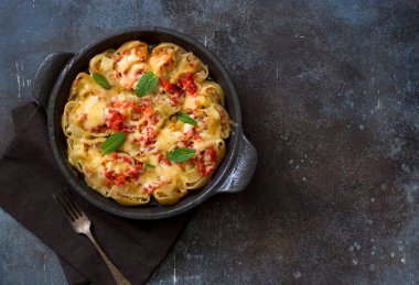 Kıyma, peynir ve domates sosuyla pişirilmiş İtalyan makarnası grunge stone arka planında pişirme tepsisi. Düz yatıyordu. Boşluğu kopyala