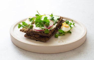 Beyaz tabakta çiğ sebzeli sağlıklı çavdar ekmeği. Seçici odak