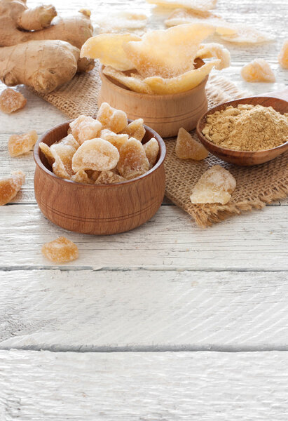 Ginger fresh root, ginger candy pieces and ginger spice on a woo