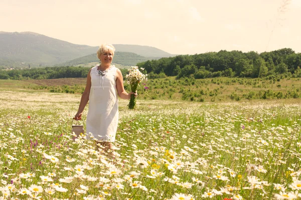 Femme âgée marchant sur le champ de fleurs — Photo