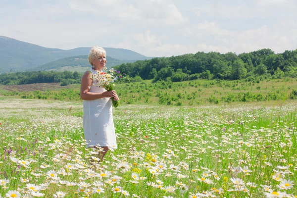 Femme âgée s'amuser sur le champ de fleurs — Photo