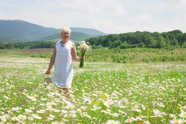 Старшая женщина веселится на цветочном поле — стоковое фото