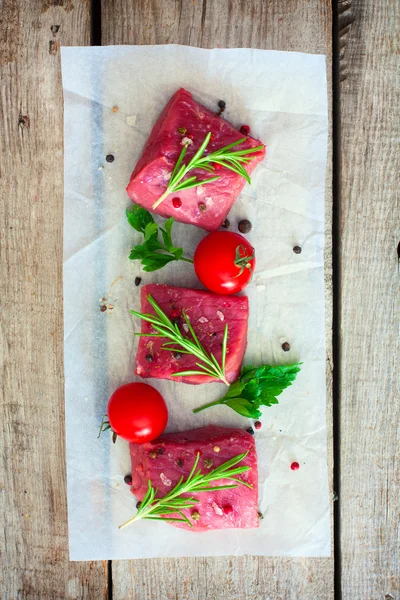 Raw beef with spices over natural wood background — Stock Photo, Image