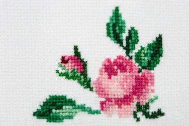 Tekstil tuvalinde haçla işlenmiş gül çiçeği