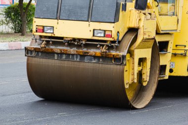 Pist yol yüzeyini sıkıştırıyor, caddede yol onarımı yapılıyor.