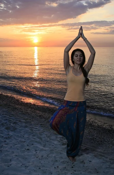 Meisje doet yoga op het strand. — Stockfoto