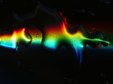 Gökkuşağı su birikintisine yansıyor. Renkler canlı ve görüntünün rüya gibi, ruhani bir kalitesi var.