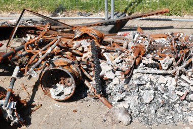 Yerde paslanmış metal ve kül yığını var. Sahne kaotik ve düzensiz.