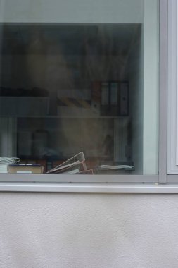 Pencerenin pervazında bir yığın kağıt var. Kağıtlar bir kutunun üstünde.