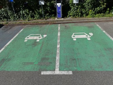 İki elektrikli araba şarj istasyonu olan bir otopark. Park yeri yeşil ve beyaz çizgisi var.