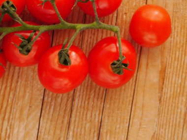 Bir grup kırmızı domates ahşap bir masanın üzerinde. Domatesler olgunlaştı ve yenmeye hazır.