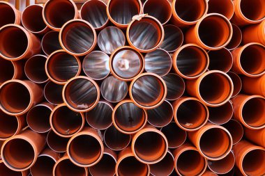 Yapım ve yenileme temaları için ideal dairesel açıklarını ve dokularını sergileyen üst üste dizilmiş turuncu PVC boruların yakın çekim görüntüsü. Kempten 'de