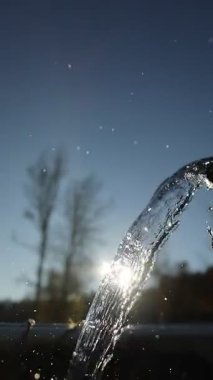 Musluktan su akıntısı akıyor. Su berrak ve gökyüzü mavi.