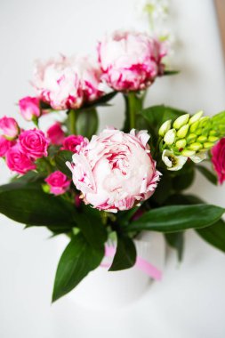 Güzel bir buket pembe şakayık ve küçük güller beyaz bir sandalyede duruyor. Düğün buketi, doğum günü. Yakın plan.