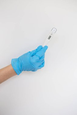 Doktorun elinde mavi lateks eldiven var. Mavi arka planda hastanın vücut sıcaklığını gösteren bir termometre var. Grip, hastalık konsepti