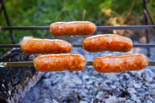 Des saucisses frites sur des brochettes. Soirées d'été près du feu, bon week-end. Gros plan. — Photo