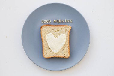 Kahvaltı için kalp şeklinde sandviç ve mavi tabakta peynir. Günaydın.