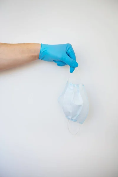 Uma Mão Luvas Azuis Segura Uma Máscara Protetora Médica Branca — Fotografia de Stock