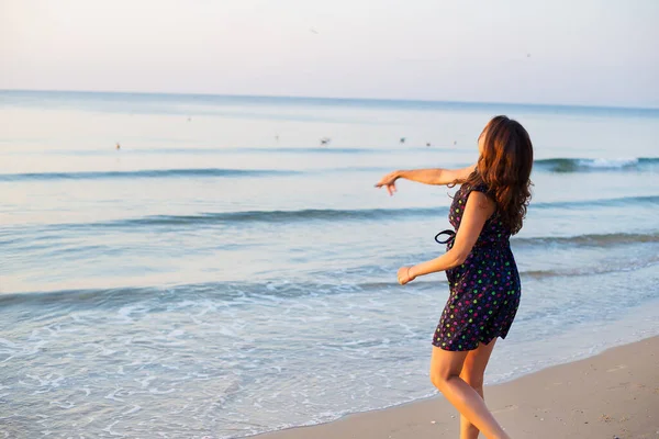 The girl throws a coin into the sea