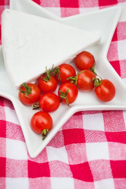 Brie peyniri ve kiraz domatesli kırmızı masa örtüsü. Kapat.