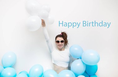 Gözlüklü mutlu kız gülümsüyor ve elinde mavi balonlar tutuyor. Yazıt için bir yer, tatil konsepti. Mutlu doğum günü mektupları