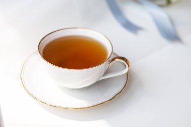 Porselen bir fincanda siyah çay. Altın kesikli güzel beyaz bir kupa. Güzel güneş ışığı. Çay töreni.