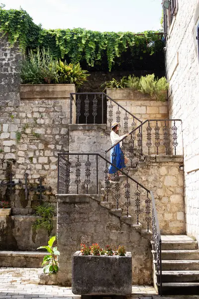 Dziewczyna Niebieskiej Sukience Słomkowym Kapeluszu Idzie Schodami Starym Mieście Kotor — Zdjęcie stockowe