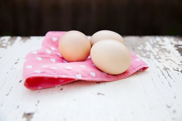 Ovos na toalha de mesa sobre fundo de madeira — Fotografia de Stock