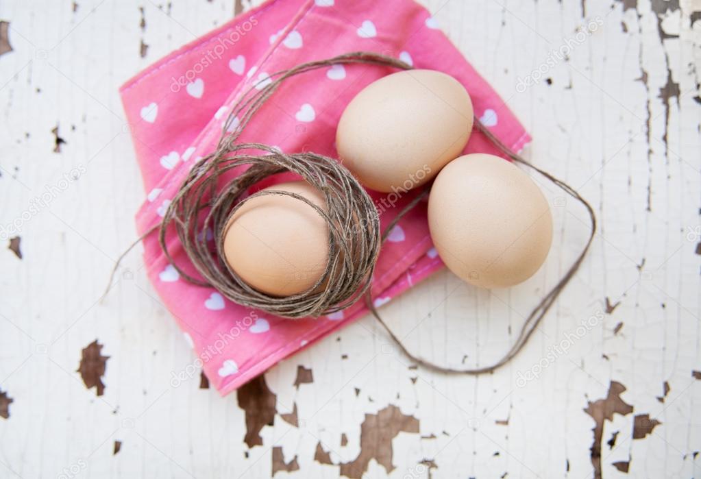 Eggs on tablecloth over wooden background