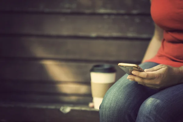 Mujer con teléfono inteligente y café al aire libre — Foto de Stock