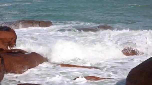 Wellen brechen auf rosa Felsbrocken an der Küste. — Stockvideo