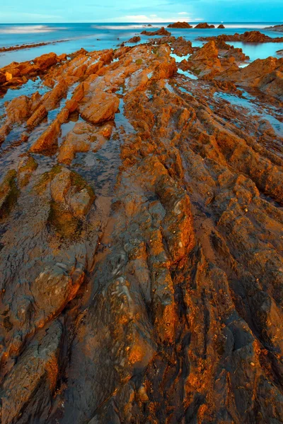 Twilight havet kusten med räfflad stratiform rock. — Stockfoto