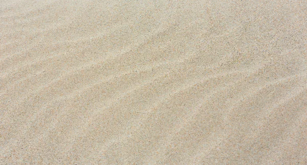 Sandhintergrund mit kaum sichtbaren Wellen. — Stockfoto