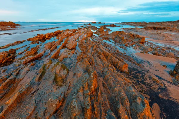 Twilight havet kusten med räfflad stratiform rock. — Stockfoto