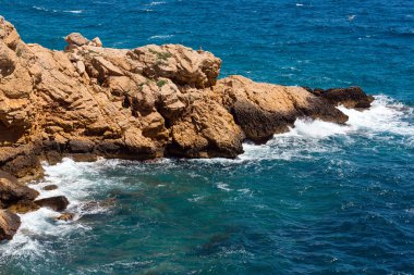 Kayalık sahilde dalgalar kopuyor.