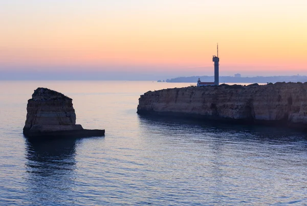 Zonsondergang uitzicht op zee kust met vuurtoren. — Stockfoto