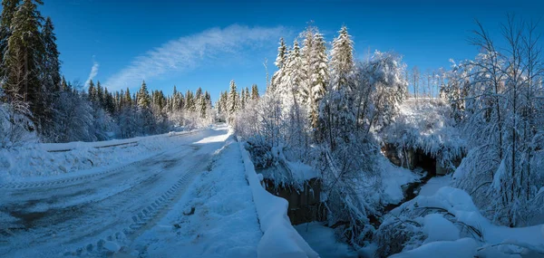 通过雪地冷杉林 雪地漂移和路边木栅栏通往偏远山区村落的二级乡村高山道路 — 图库照片